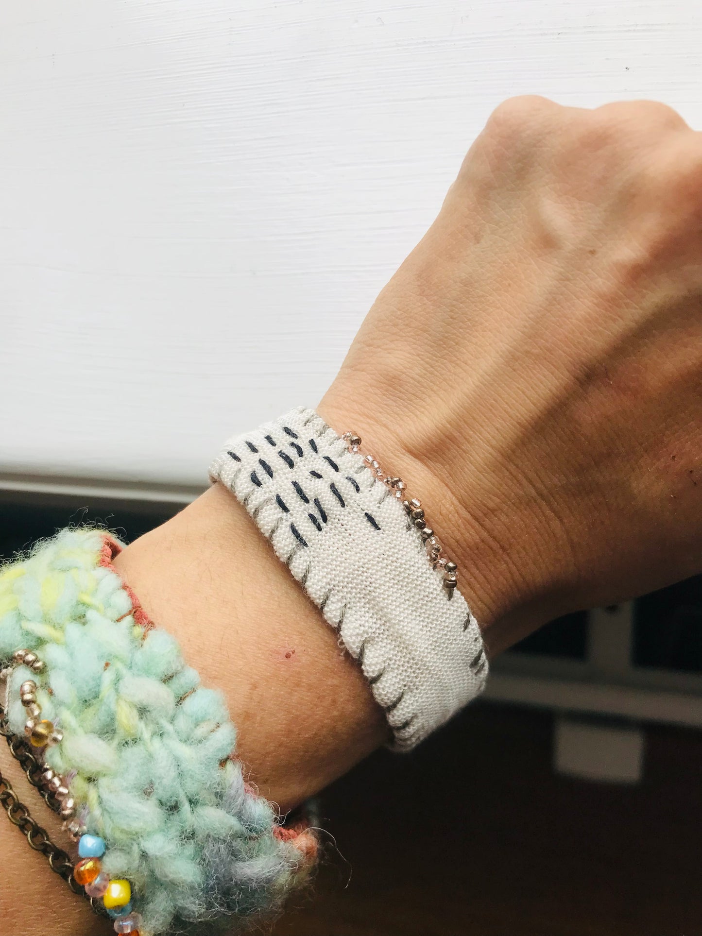 Håndsyede stofarmbånd med håndspundet garn og perlebroderi. 2048